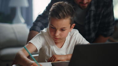 父帮助孩子家庭作业微笑父亲儿子电脑屏幕